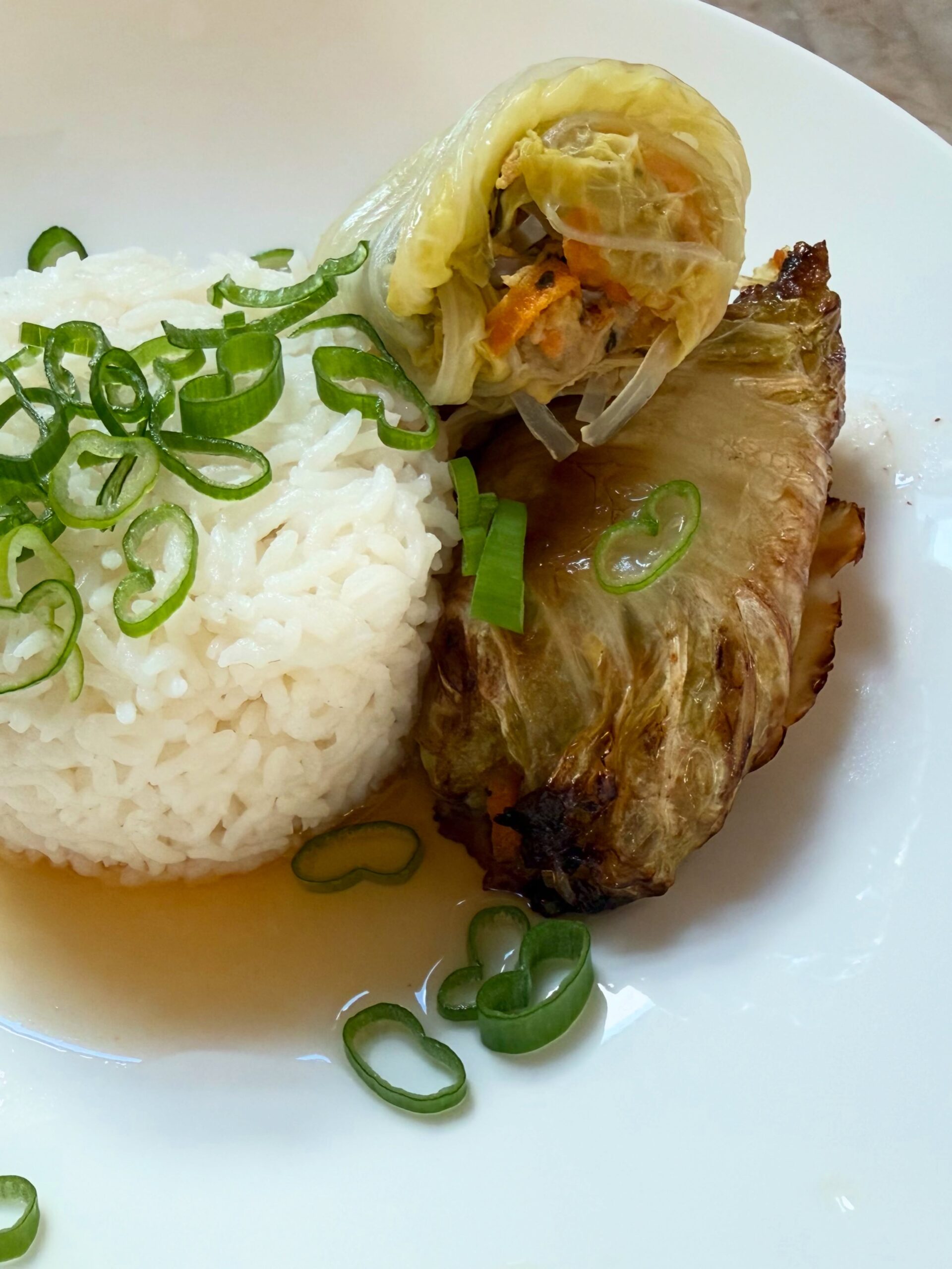 Cabbage roll plated with rice and scallions