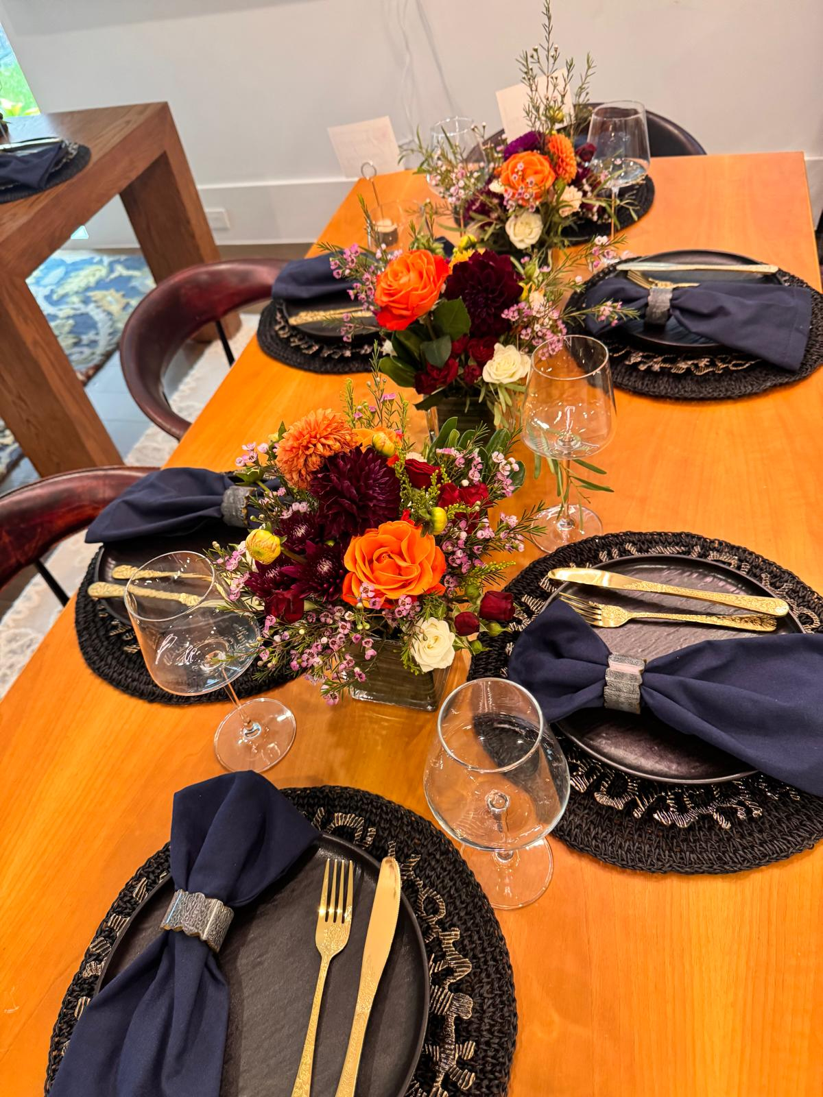 Dinner table set with fall florals, navy napkins and gold flatware